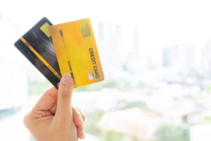 The hand of the woman holding two credit cards.