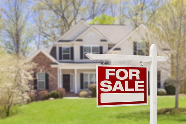 For sale sign in front yard of house