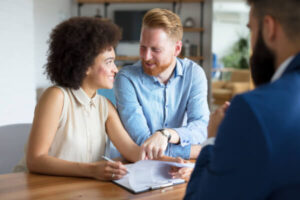 Couple sitting with lender signing paperwork for a house