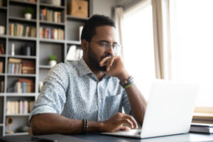 Man sitting at computer trying to decide if debt consolidation is a good idea