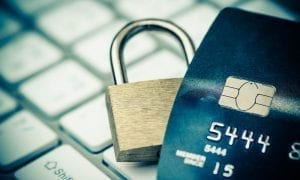 Close up of brass lock behind blue credit card on top of keyboard