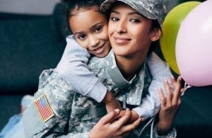 African american daughter hugging her mother in military uniform with balloons