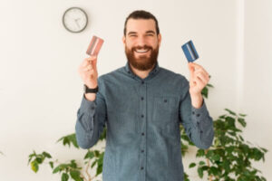 happy man showing two credit card, red and blue debit card